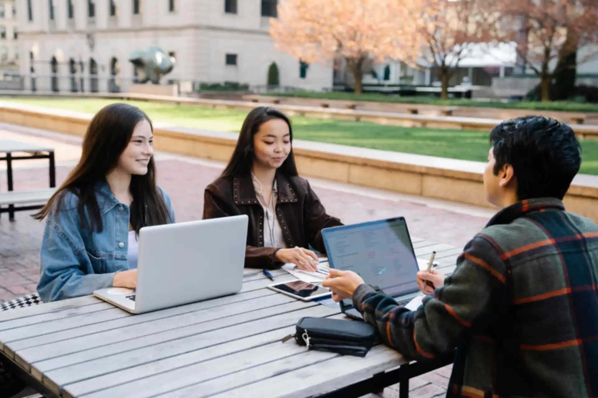 Students working together on laptops in a university campus courtyard